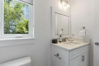 a white bathroom with a sink and a mirror at Inlet Beach Retreat Golf Cart Bikes + Pool in Inlet Beach