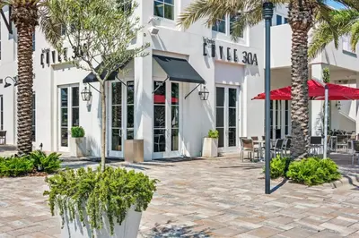 a courtyard with palm trees in front of a building at Family Friendly Vacation Rental at 30Ave Beach Retreat in Inlet Beach in Rosemary Beach