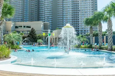 a fountain in a swimming pool with palm trees at Emerald Beach 1631 by Emerald Coast Retreats in Panama City Beach