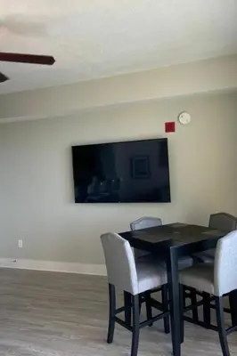 a dining room table with chairs and a tv on a wall at Calypso III Stunning Oceanview next to Pier Park Mall in Panama City Beach