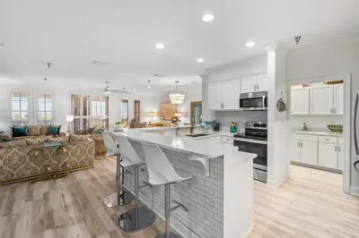 a kitchen and living room with white cabinets and a bar at Southern Charm 409, Village of South Walton in Rosemary Beach