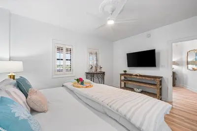 a white room with a large bed and a tv at Southern Charm 409, Village of South Walton in Rosemary Beach