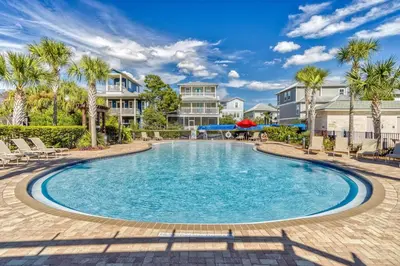 a pool with palm trees and houses in the background at Southern Charm 409, Village of South Walton in Rosemary Beach