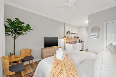 a white bedroom with a white bed and a tv at Village of SoWal B203 in Rosemary Beach