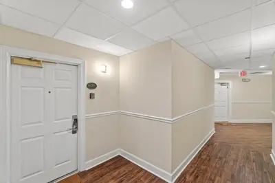 an empty room with a white door and wooden floors at Village of SoWal B203 in Rosemary Beach