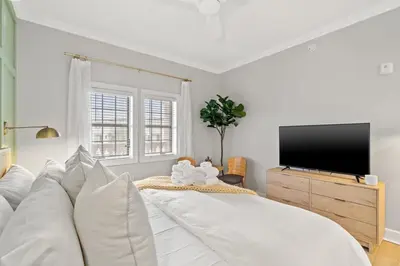 a white bedroom with a large bed and a flat screen tv at Village of SoWal B203 in Rosemary Beach