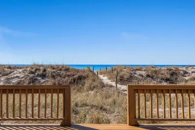 two wooden benches sitting on a deck looking at the beach at 9620 Beach Blvd in Panama City Beach