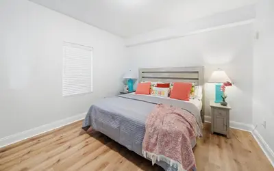 a white bedroom with a bed with orange and blue pillows at Spacious 3BR + Bunk Laketown Wharf Condo Sleeping 10 Near Beach in Panama City Beach