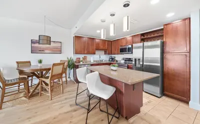 a kitchen with wooden cabinets and a table with chairs at Spacious 3BR + Bunk Laketown Wharf Condo Sleeping 10 Near Beach in Panama City Beach
