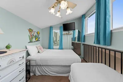 two beds in a room with blue walls and windows at Quiet East End PCB Condo w/ Direct Beach Access & Balcony in Panama City Beach