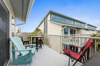 a balcony with chairs and tables on a house at Quiet East End PCB Condo w/ Direct Beach Access & Balcony in Panama City Beach