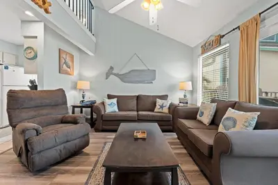 a living room with two couches and a table at Quiet East End PCB Condo w/ Direct Beach Access & Balcony in Panama City Beach