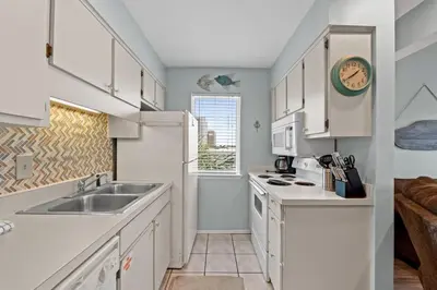 a kitchen with white cabinets and a sink at Quiet East End PCB Condo w/ Direct Beach Access & Balcony in Panama City Beach