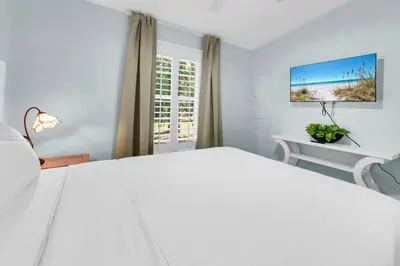 a bedroom with a large white bed and a window at Gone to the Beach cozy small home located near beach in Santa Rosa Beach