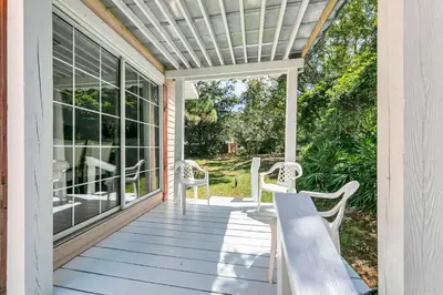 a porch with chairs and a bench on it at Gone to the Beach cozy small home located near beach in Santa Rosa Beach