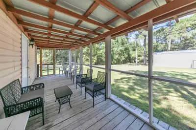 a screened porch with chairs and tables and windows at Gone to the Beach cozy small home located near beach in Santa Rosa Beach