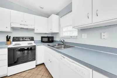 a kitchen with white cabinets and a sink at Gone to the Beach cozy small home located near beach in Santa Rosa Beach
