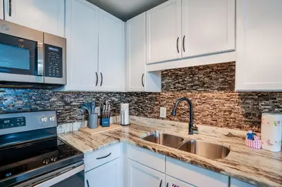 a kitchen with white cabinets and a sink at Wharftown Retreat - 8ppl in Panama City Beach