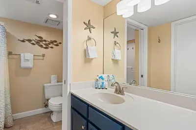 a bathroom with a sink and a toilet and a mirror at Commodore 0702 in Panama City Beach