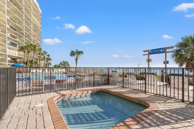 a swimming pool with a fence next to a resort at Commodore 0702 in Panama City Beach