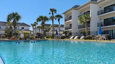 a swimming pool in front of a building with palm trees at Emerald Hill 23 - The Little Pearl in Santa Rosa Beach