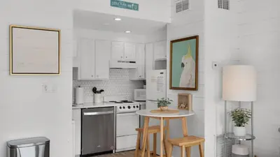 a kitchen with white cabinets and a table with stools at Emerald Hill 23 - The Little Pearl in Santa Rosa Beach
