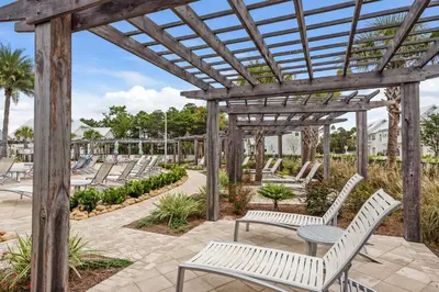 a wooden pergola with white benches and tables at Prominence B - 30 Ray in Inlet Beach