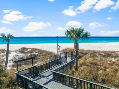 a staircase leading to the beach with palm trees at Sunbird of Panama City Beach 503E in Panama City Beach
