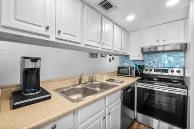 a kitchen with white cabinets and a sink at Sunbird of Panama City Beach 503E in Panama City Beach