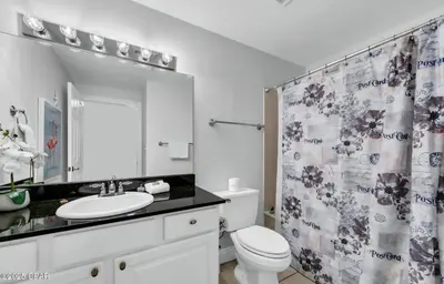 a bathroom with a sink and a toilet and a shower curtain at The Emerald Nest in Panama City Beach