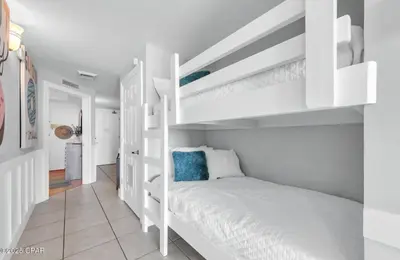 a bedroom with white bunk beds in a white room at The Emerald Nest in Panama City Beach