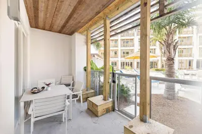 a balcony with a table and chairs and a tree at Poolside Paradise in Inlet Beach
