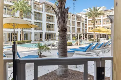 a resort with a pool and chairs and a palm tree at Poolside Paradise in Inlet Beach