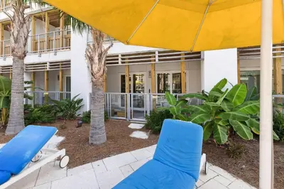two blue chairs and an umbrella in front of a building at Poolside Paradise in Inlet Beach