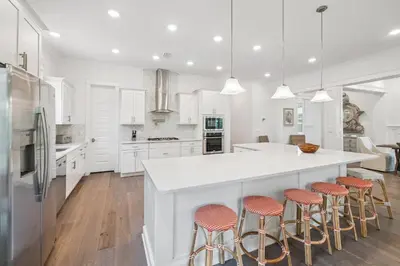 a kitchen with white cabinets and a large island with bar stools at Our Oasis in Inlet Beach