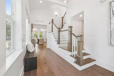 a living room with white walls and wooden stairs at Our Oasis in Inlet Beach