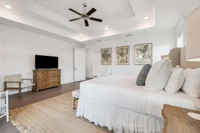 a white bedroom with a bed and a flat screen tv at Our Oasis in Inlet Beach