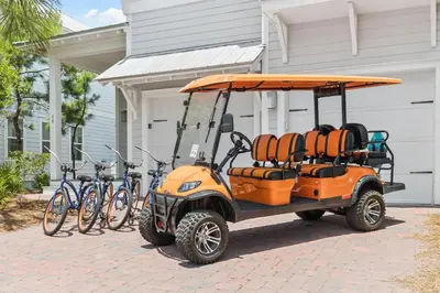 an orange golf cart parked in front of a house with bikes at Our Oasis in Inlet Beach
