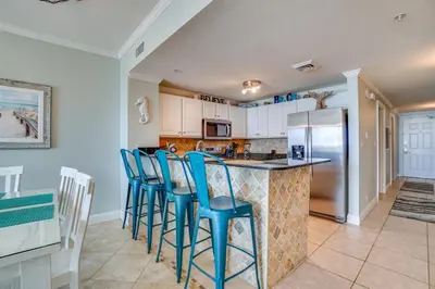 a kitchen with blue bar stools and a counter top at Calypso 1-202 by Emerald Coast Retreats in Panama City Beach