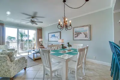 a dining room and living room with a table and chairs at Calypso 1-202 by Emerald Coast Retreats in Panama City Beach