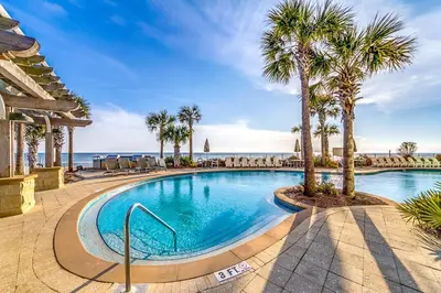 a swimming pool with palm trees and the ocean at Rare Corner-Unit at AQUA 201 Private Elevator, Multiple Balconies Sunset Views in Panama City Beach
