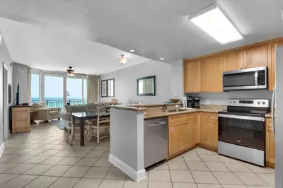 a kitchen with wooden cabinets and a dining room at Aqua 0309 in Panama City Beach