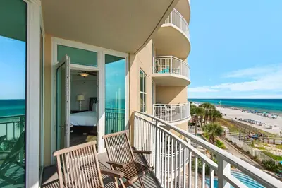 a balcony with two chairs and a bed and the ocean at Aqua 0309 in Panama City Beach