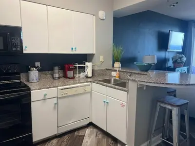 a kitchen with white cabinets and a sink at Beach Please in Panama City Beach
