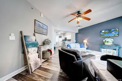 a living room with a couch and a ceiling fan at Beach Please in Panama City Beach