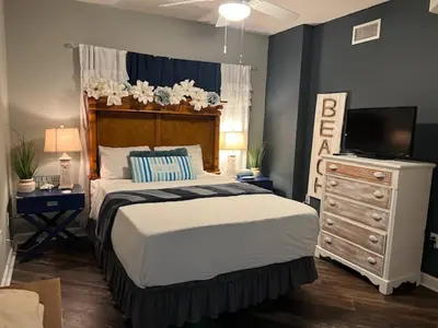a bedroom with a bed and a dresser with a television at Beach Please in Panama City Beach