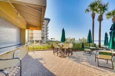 a patio with chairs and tables and umbrellas at Scenic Balcony and Resort Perks PCB Condo! in Panama City Beach