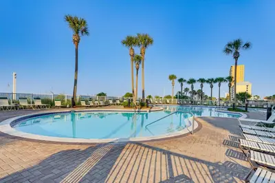 a large swimming pool with palm trees and chairs at Scenic Balcony and Resort Perks PCB Condo! in Panama City Beach