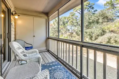a screened in porch with chairs and windows at Somewhere in the Sun in Santa Rosa Beach