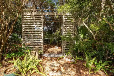 an old wooden arch in the middle of a garden at Somewhere in the Sun in Santa Rosa Beach